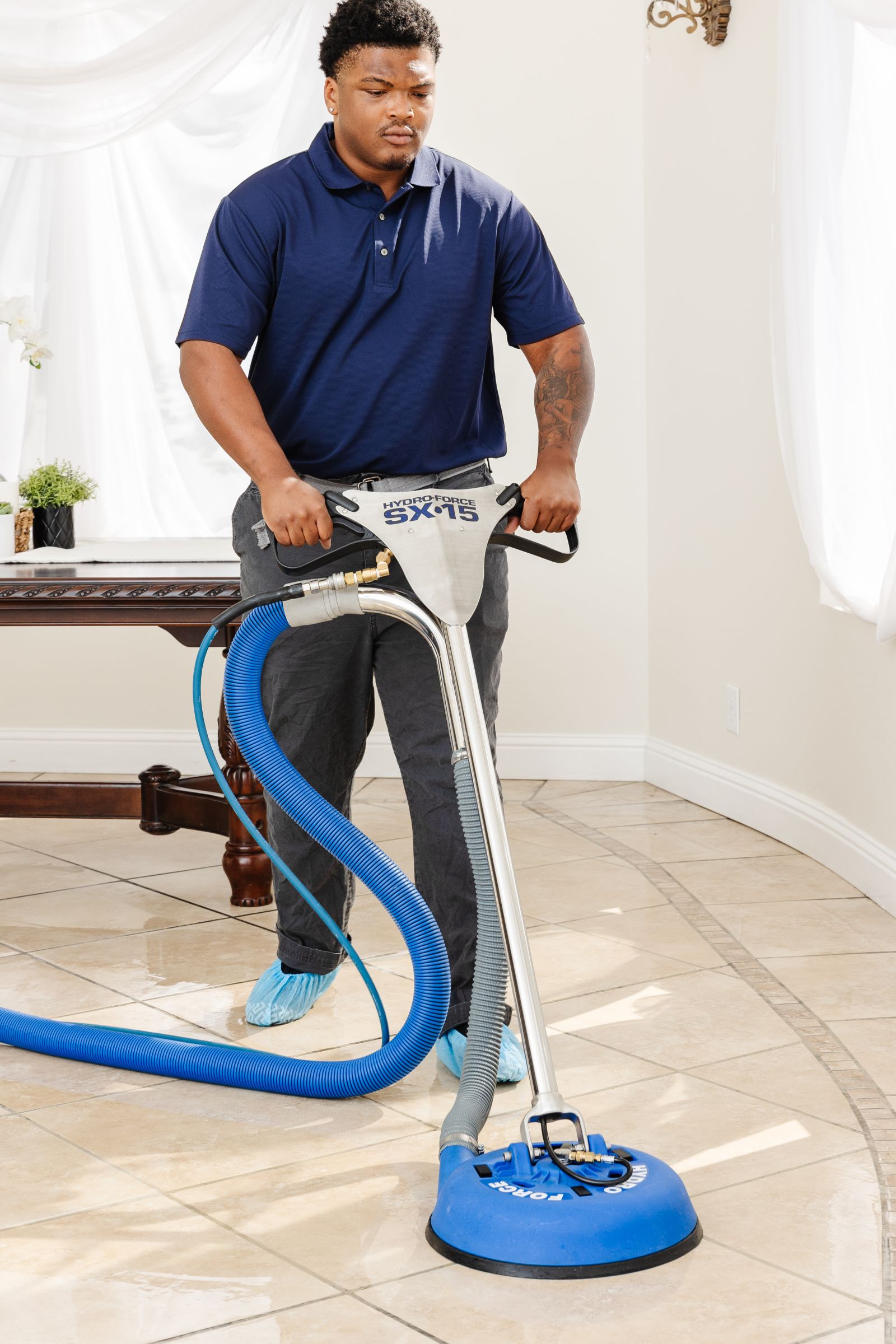 male Zerorez&reg; technician using a tile and grout cleaning tool to clean beige tile flooring in a dining room