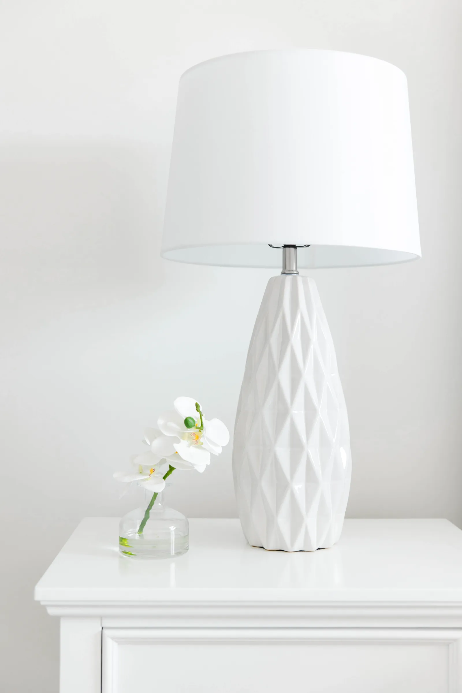 white table with white flower small vase and lamp