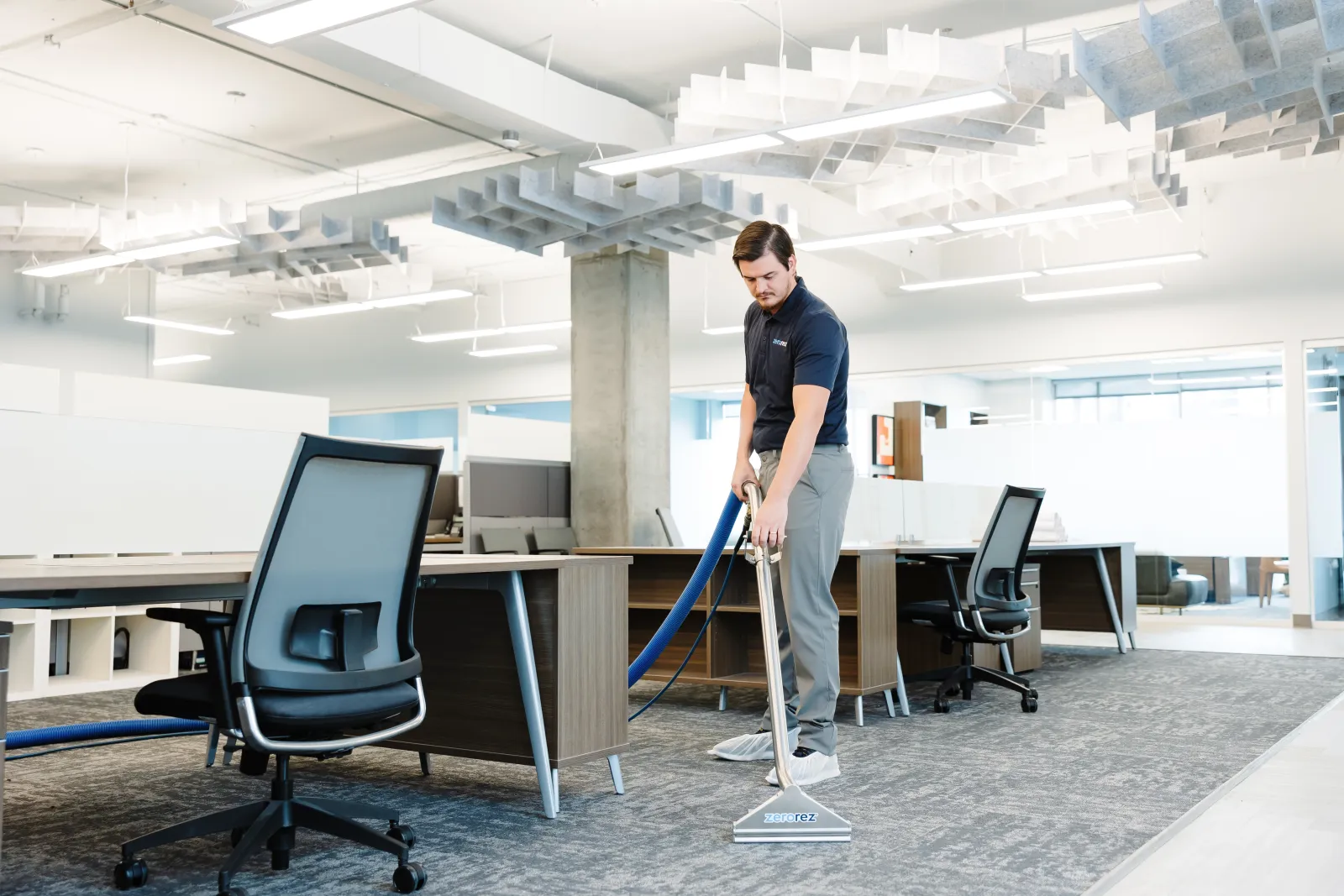 technician holding carpet cleaning wand in an office space